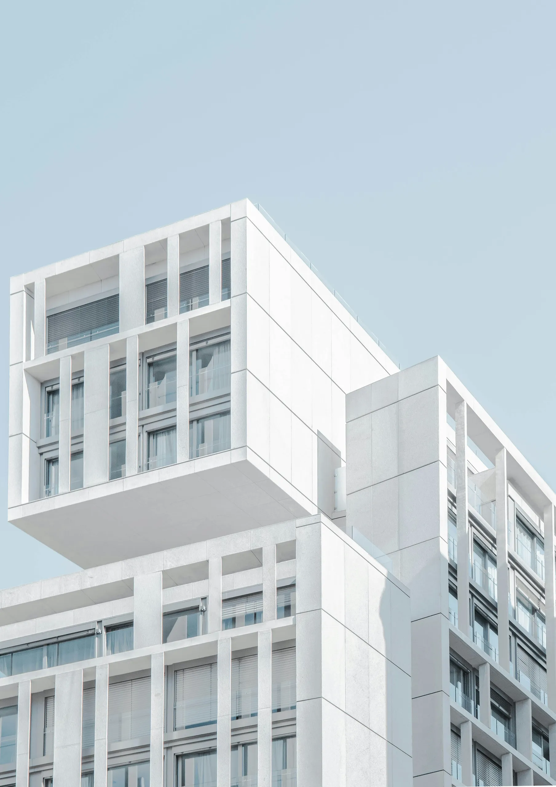 Edificio modernista blanco con un volumen en voladizo sobre un fondo de cielo claro